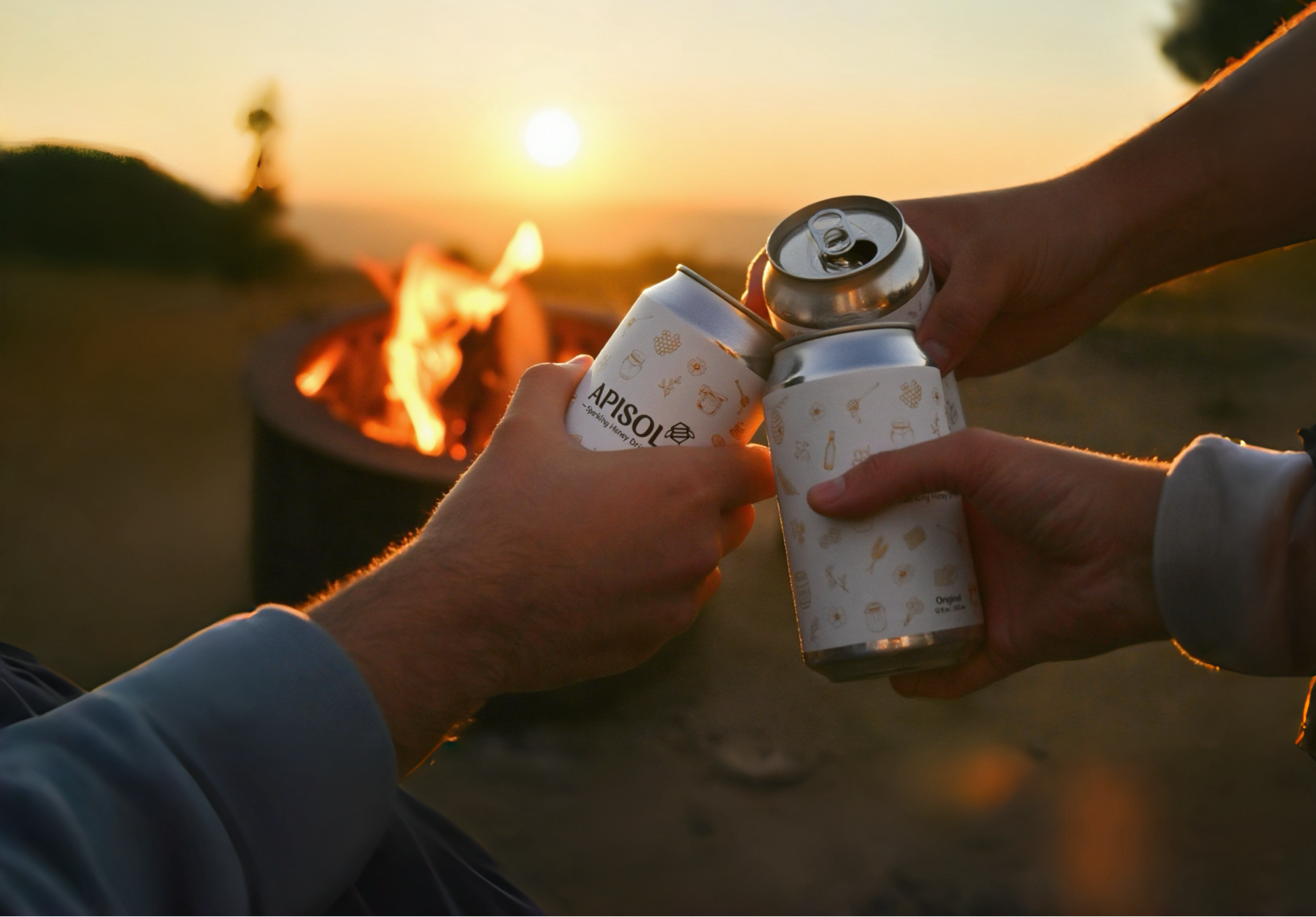Three cans of Apisol being held up in a cheers gesture during camping, against a sunset background in adventure